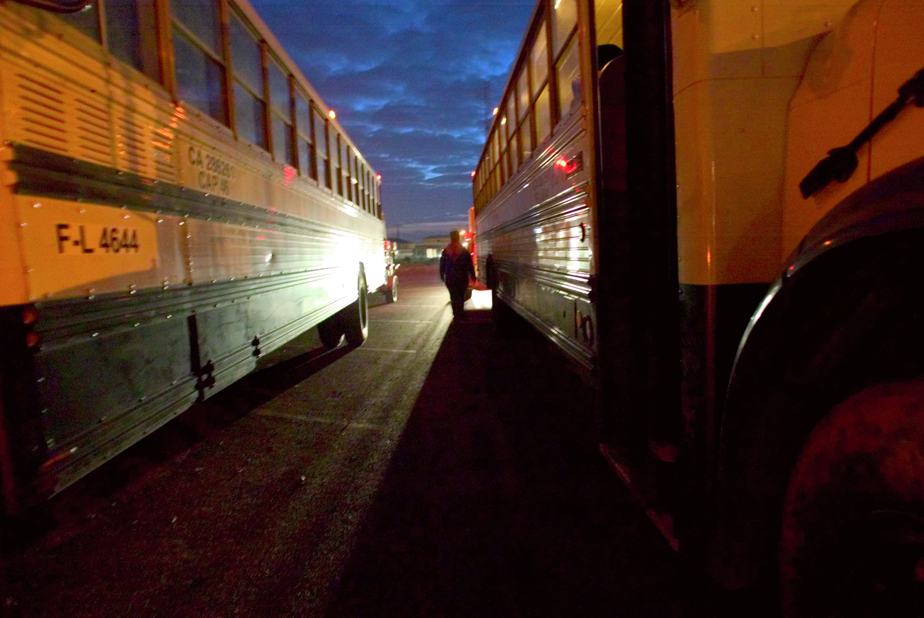 Farmworkers board buses in the early morning hours in Huron, California.